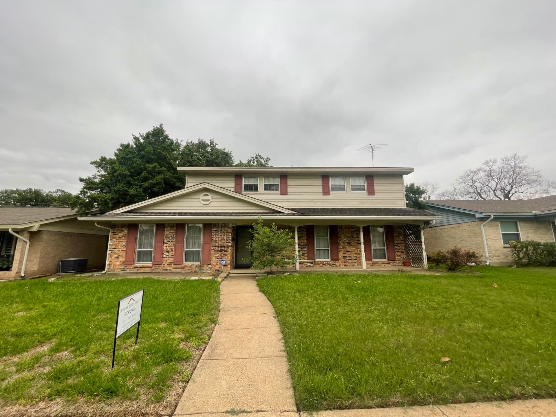 Front elevation of a two-story brick and siding home in the North Dallas area on an overcast day before a roof inspection