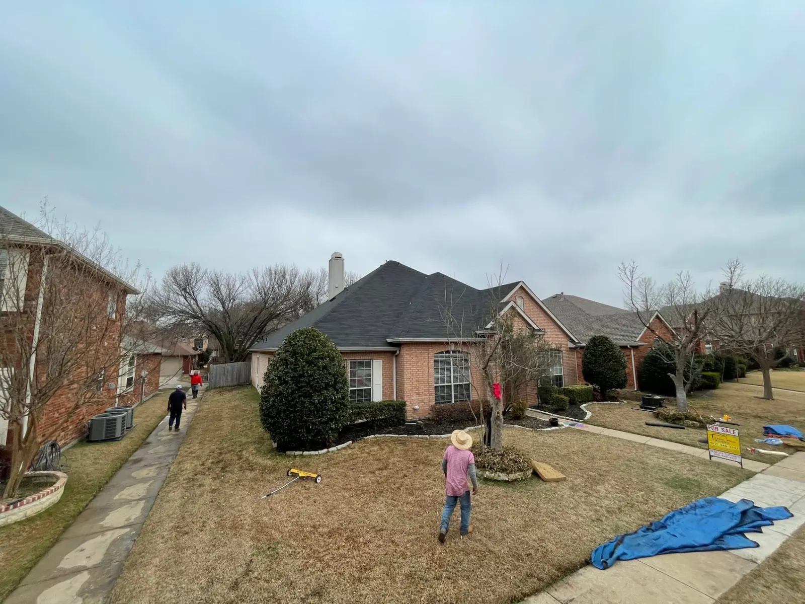 Homebase Roofing crew mid tear-off on a single-story brick home in the North Dallas area, with a magnetic nail sweeper on the lawn and tarps staged at the curb